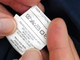 Cropped close up of hands holding the care label on a garment